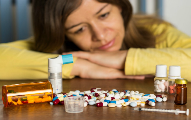 prescription_pills_foreground_sad_woman_background_head_slumped_on_table